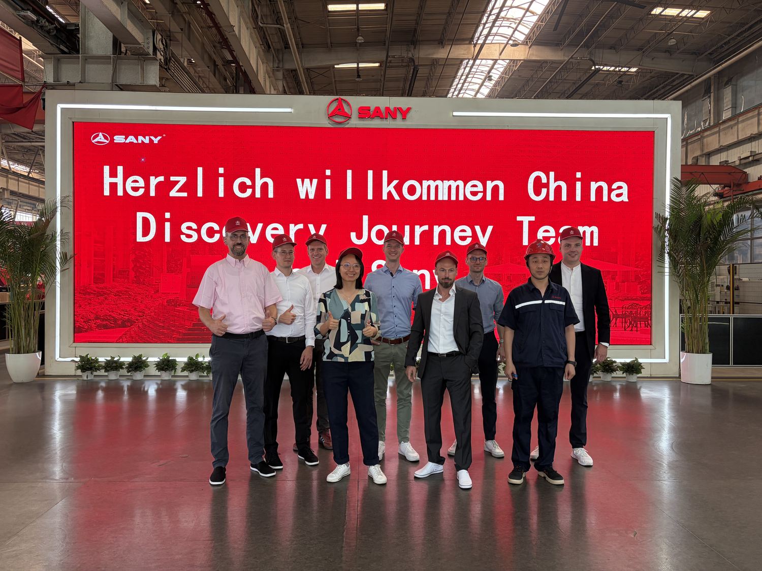 Gruppe vor der Anzeigetafel „Herzlich willkommen China Discovery Journey Team“